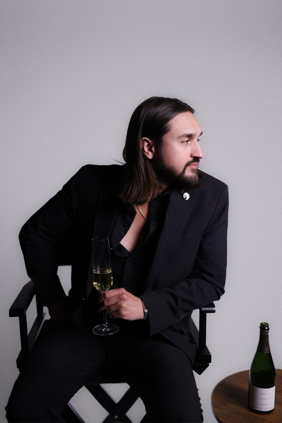 Nico Antuna Cooper, seated, in a black suit with a glass of Champagne and the Court of Master Sommeliers pin on his lapel